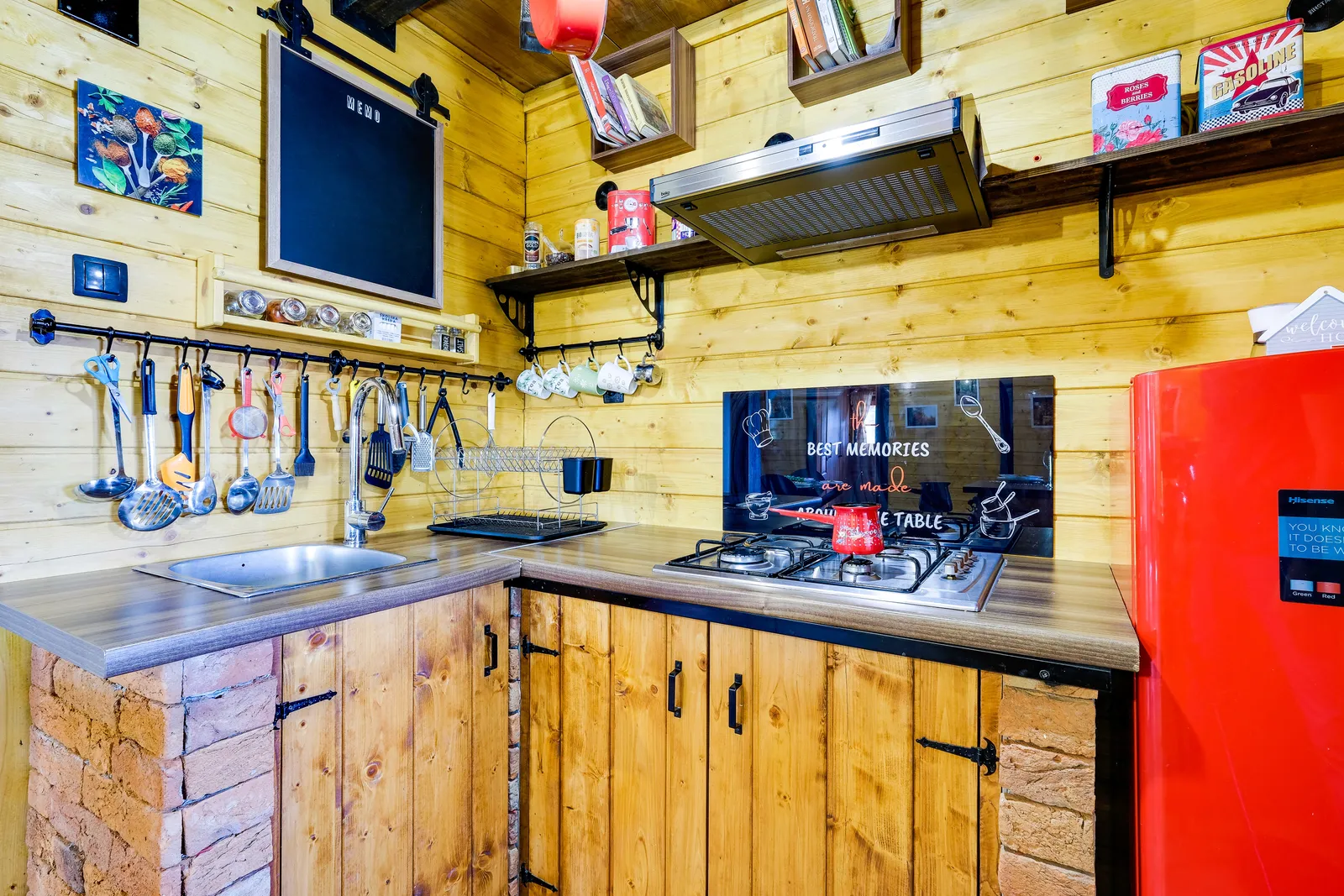 Rustikale Küche mit rotem Kühlschrank, Gasherd und aufgehängtem Küchenzubehör